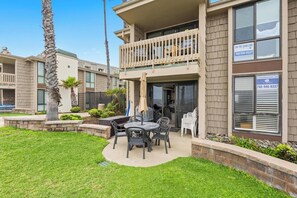 A two-story building with a balcony, outdoor seating area, and a well-maintained lawn. - D27 North Coast Village - Oceanfront, ground level cottage, Amazing Direct Ocean Views (Oceanside)