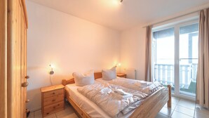 A bedroom with a wooden bed, two bedside tables, a nightstand, and a window with curtains.