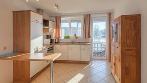 A modern kitchen with wooden cabinets, a central island, and a view of the outdoors.