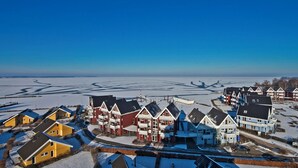 A coastal residential area with houses along the shoreline, featuring a mix of single and multi-story buildings with balconies, and a clear view of the sea. - Mitteldeck 504 - Cozy vacation apartment with a view of the Müritz (Rechlin-Nord)