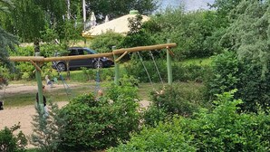 Un parque con un columpio, un coche y un lago.