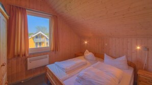 Acogedora habitación de cabaña de madera con dos camas, una ventana y un radiador.