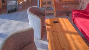 Interior acogedor de una cabaña con detalles de madera, un dormitorio en altillo, un comedor y una sala de estar con un sofá rojo.