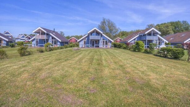 Een rij blauwe huizen met witte details en een verzorgd gazon ervoor.