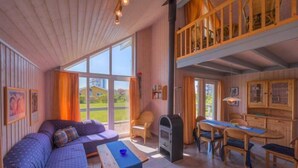 Een gezellig cabin interieur met een groot raam, een bank, een eettafel en een keukenhoek.