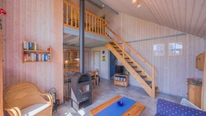 Een gezellig interieur met een houten trap, een open haard en een balkon.