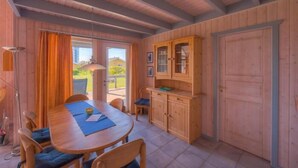 Een houten interieur met een eettafel, stoelen, een kast en een deur.