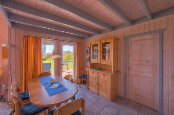 A wooden interior with a dining table, chairs, a cabinet, and a door.