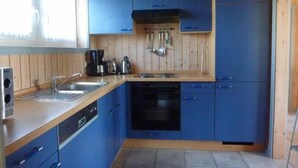 A compact kitchen with blue cabinets, a dishwasher, a stove, and a sink.