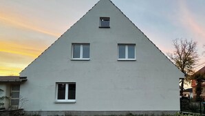 Uma casa triangular com tr ês janelas e uma pequena janela no sótão.