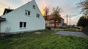 Um bairro residencial com uma casa branca, uma casa com telhado vermelho e um caminho de entrada pavimentado.