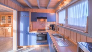 A modern kitchen with wooden cabinets, a built-in oven, and a large window with curtains.