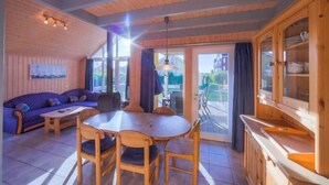 A wooden interior with a dining area, sofa, and kitchen cabinets.