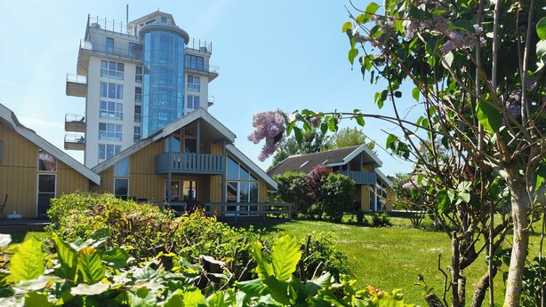 A residential area with modern houses, a large building with balconies, and lush greenery.