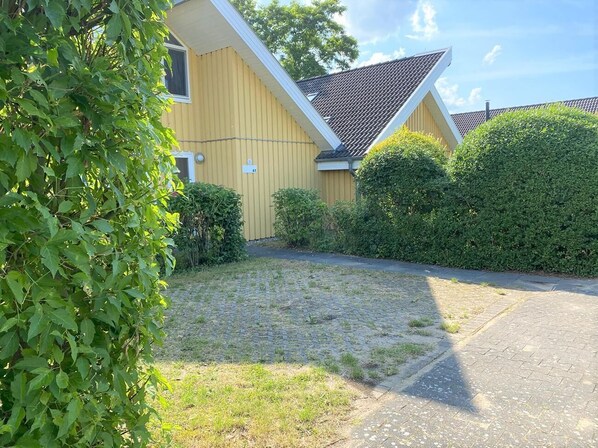 A yellow building with a sloped roof and a paved driveway.