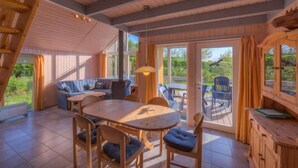 Un interior de madera con zona de comedor, un sofá y una escalera.