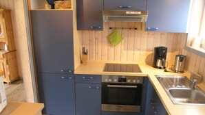 A compact kitchen with blue cabinets, a Bosch oven, a sink, and a coffee maker. - Seeschwalbe Classic 63 - Spacious vacation home with its own sauna (Rechlin-Nord)