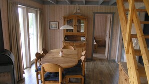 A wooden dining room with a large table, chairs, a chandelier, and a wooden cabinet. - Seeschwalbe Classic 63 - Spacious vacation home with its own sauna (Rechlin-Nord)