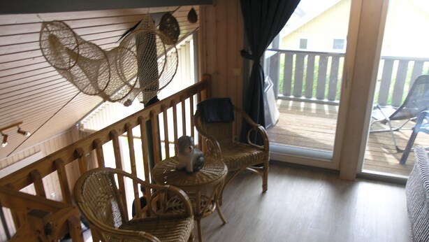 A balcony with wicker furniture, a ceiling fan, and a view of the outside deck. - Seeschwalbe Classic 63 - Spacious vacation home with its own sauna (Rechlin-Nord)
