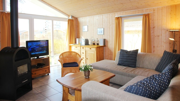 A cozy living room with a fireplace, sofa, television, and wooden furniture.