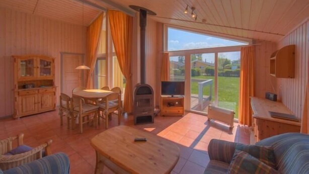 A cozy living room with a wooden interior, a fireplace, a television, and a large window offering a view of the outdoors.