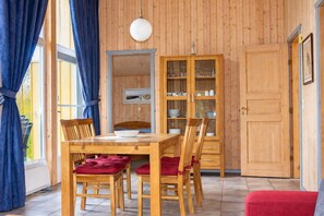 A dining area with a wooden table and chairs, a cabinet with glass doors, and a red bench.