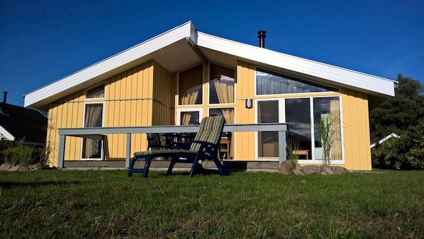 Un edificio moderno de color amarillo con ventanas grandes y un patio cubierto.