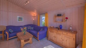 Una habitación acogedora con un sofá azul, un armario de madera y una mesita.
