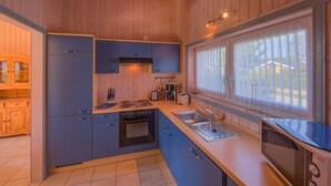 Cocina compacta con armarios de madera, estufa, lavaplatos y una ventana que proporciona luz natural.
