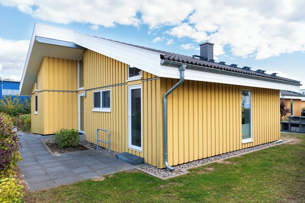 Un edificio giallo con tetto spiovente, un piccolo portico e un vialetto lastricato che conduce all'ingresso.