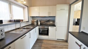 Una cocina moderna con armarios blancos, encimera negra y estufa de acero inoxidable.