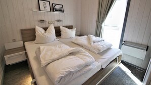 Una cama doble con ropa blanca de cama, una mesita de noche con una lámpara y un cuadro en la pared.