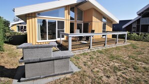 Una casa moderna con amplios ventanales, una terraza y base de piedra.