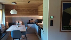 Eine moderne Küche mit Holzbalkendecke, einem Esstisch mit Stühlen und einer Hängeleuchte.
