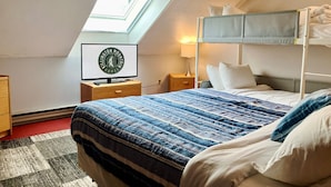 Un dormitorio con literas, un escritorio con computadora, una lámpara y un tragaluz.