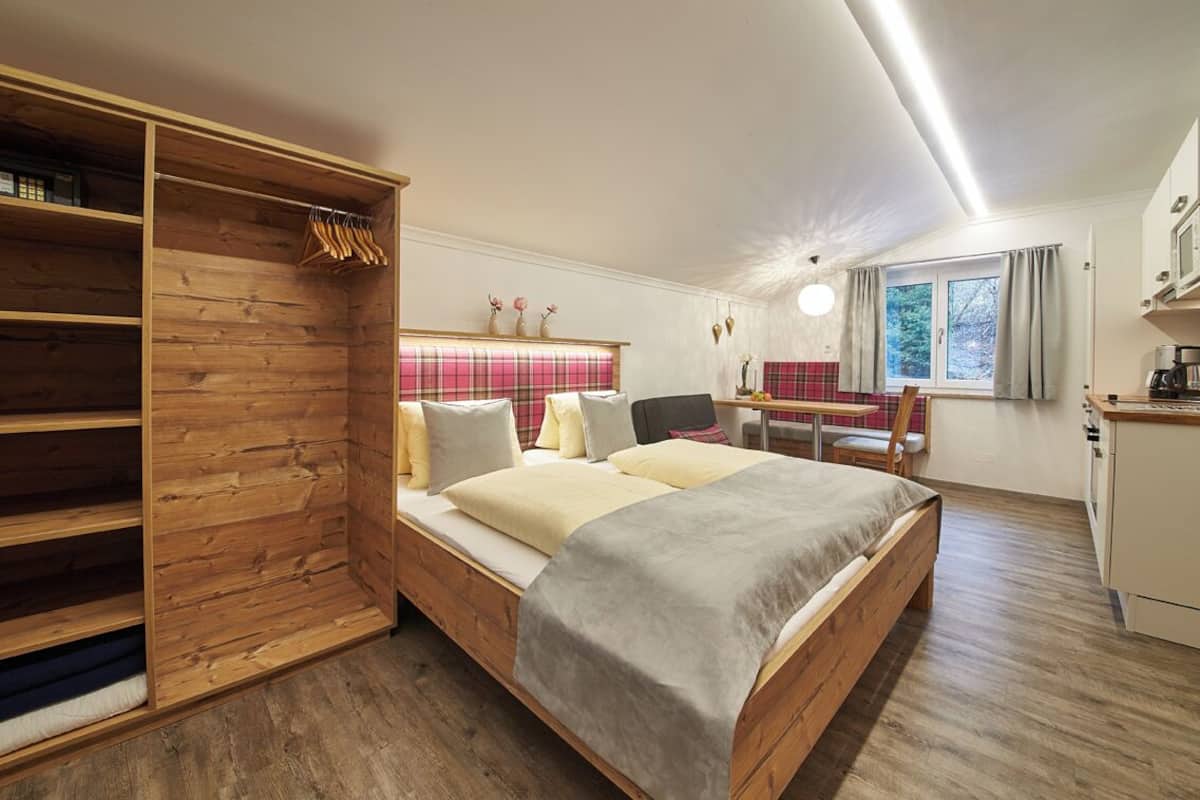 Ein Schlafzimmer mit einem Holzbett, einem Schreibtisch und einer Küchenzeile.
