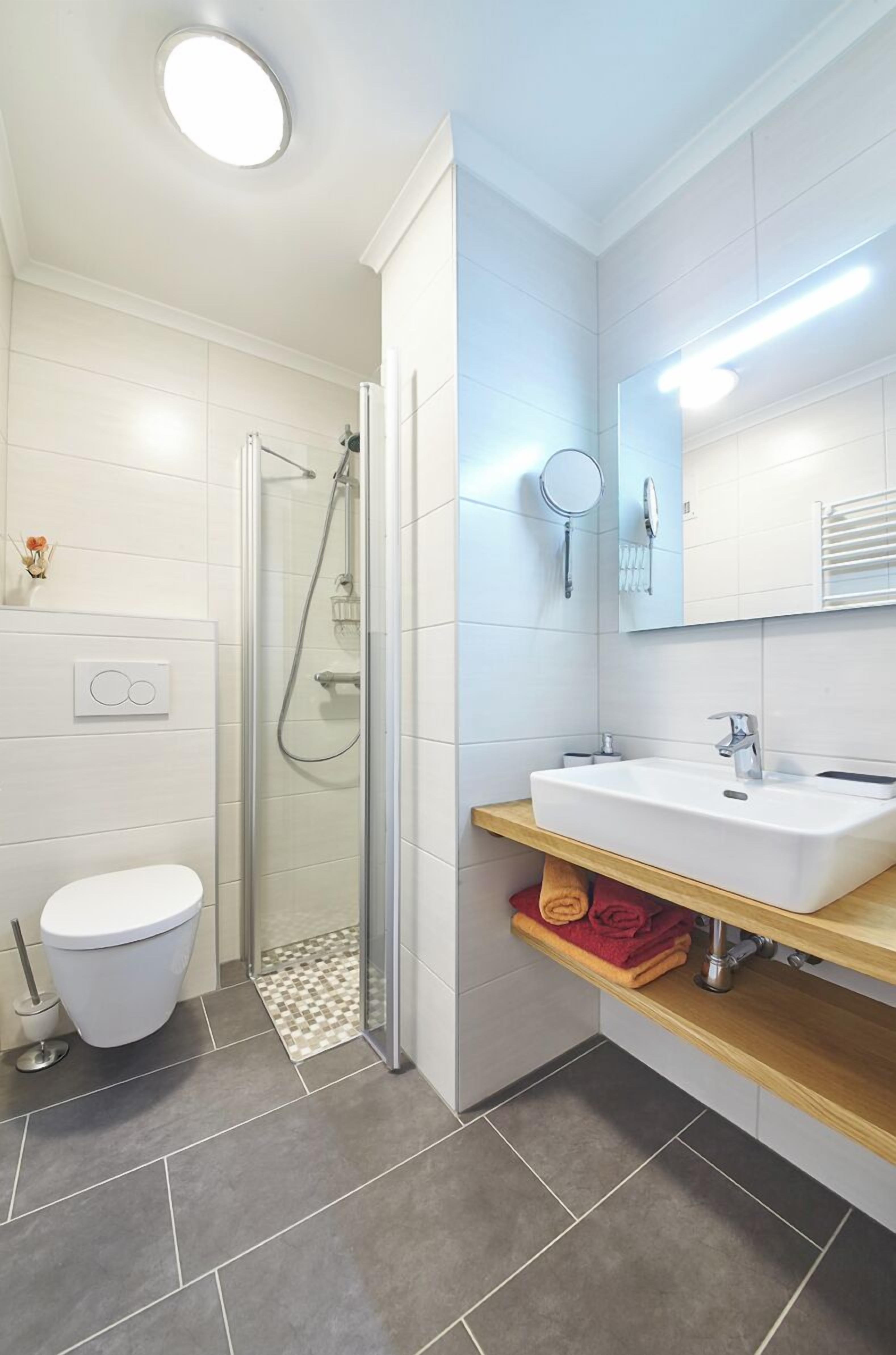 A modern bathroom with a shower, toilet, and sink.