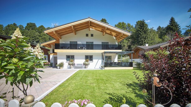 A two-story house with a wooden roof, a balcony, and a well-maintained lawn.