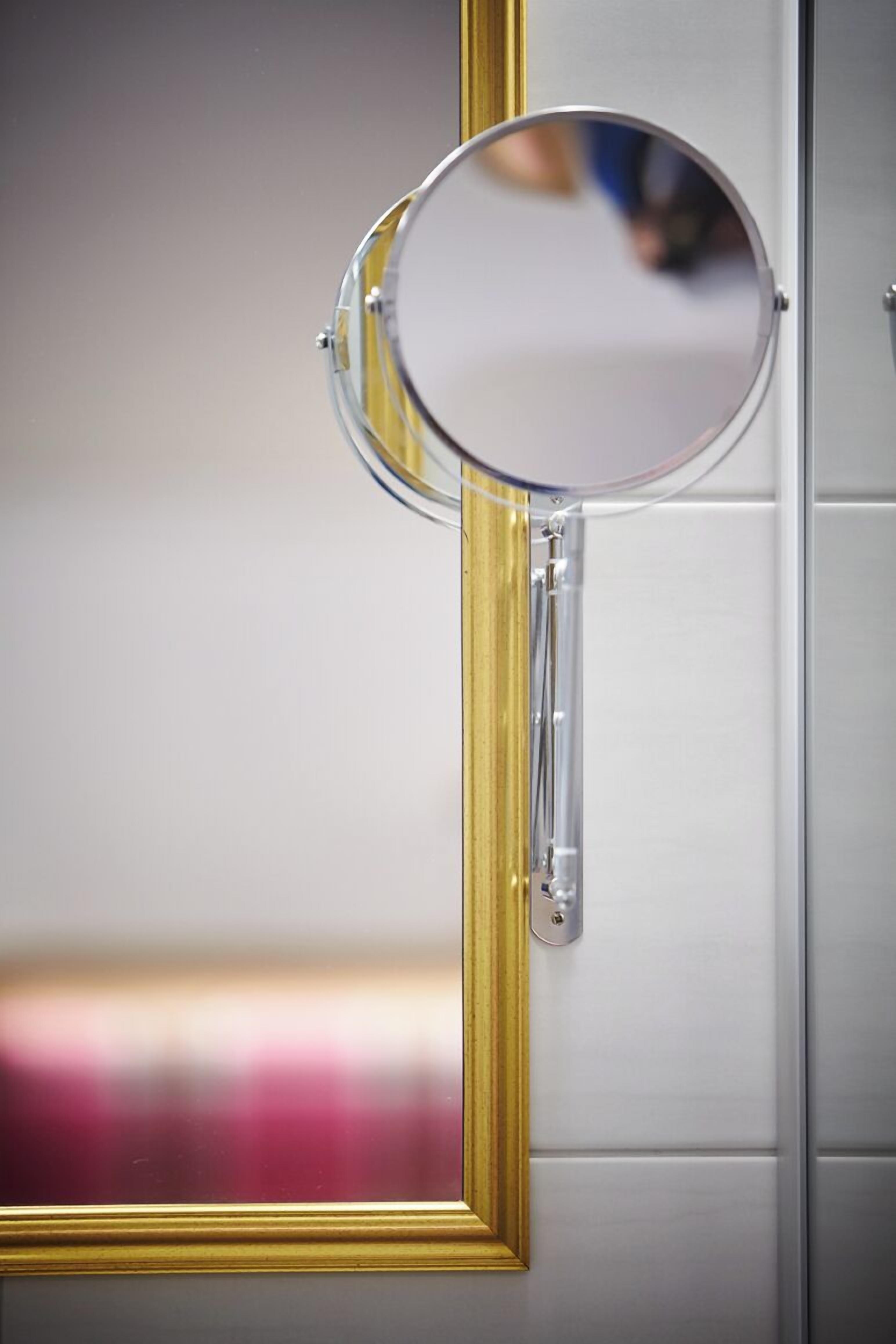 Een spiegel met gouden lijst bevestigd aan een muur.