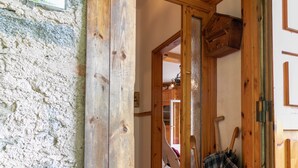 Ein rustikales Holzinnenambiente mit einer Steinswand, einer Holztür und einem kleinen Holz-Eimer mit einem karierten Beutel.