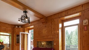 Ein Holzhäuschen-Interieur mit einem violetten Sofa, einem Essbereich mit Tisch und Stühlen und einem Kamin aus Stein.