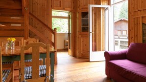 Ein Holzinterieur mit einer Treppe, einem Esstisch mit Stühlen und einer Couch.