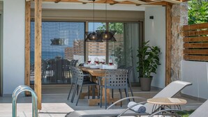 An outdoor dining area with a wooden pergola, a table set for four, and a potted plant.