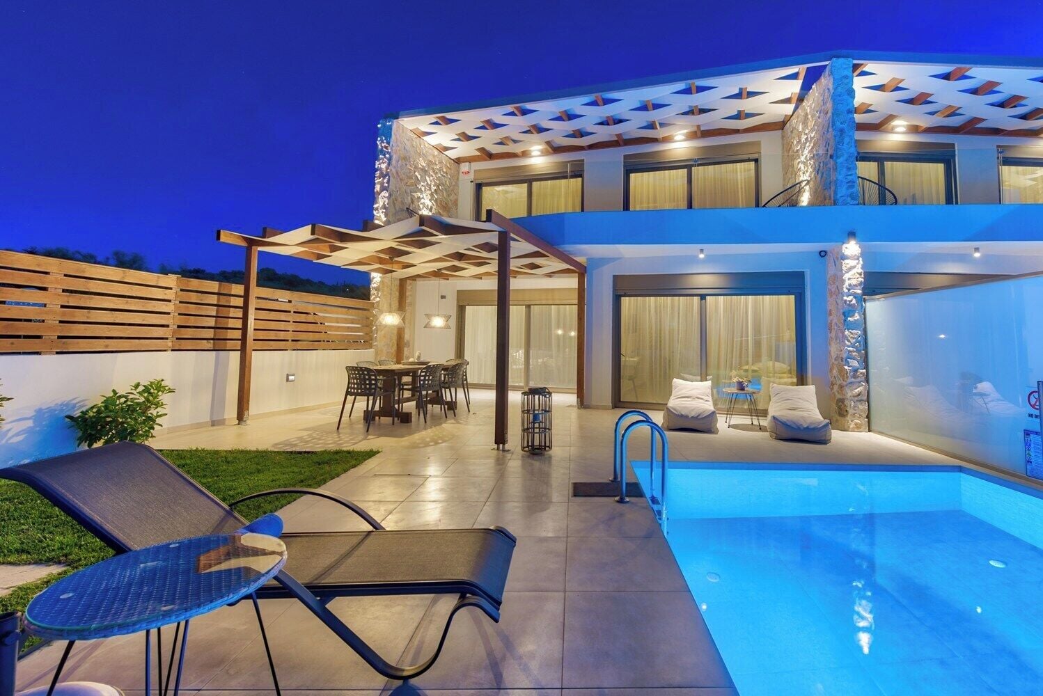 A modern house with a swimming pool, outdoor seating, and a covered patio area.