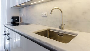 A modern kitchen with a stainless steel sink, a black coffee machine, and a sleek countertop. - Morais Soares 131 (Lisbon)