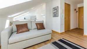 A modern living room with a grey sofa, brown cushions, a black and white rug, and a wooden floor. - Morais Soares 131 (Lisbon)