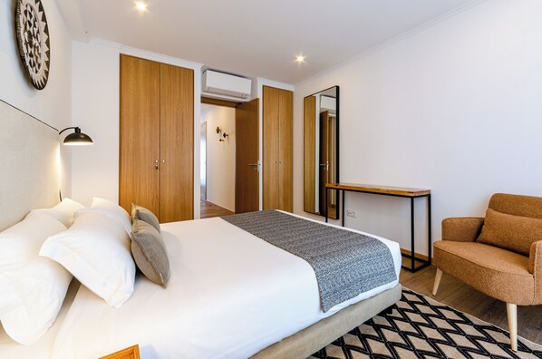 Una habitación de hotel moderna con una cama grande, un sofá, un escritorio y un armario.