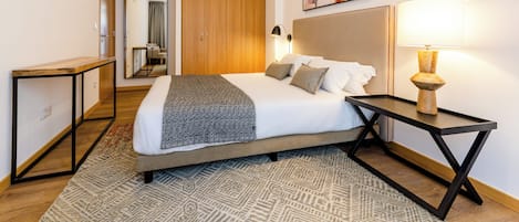 Una habitación de hotel con cama, mesita de noche, lámpara y espejo.