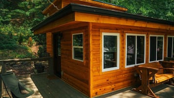 Eine Holzhütte mit einer Terrasse, großen Fenstern und einer Tür.