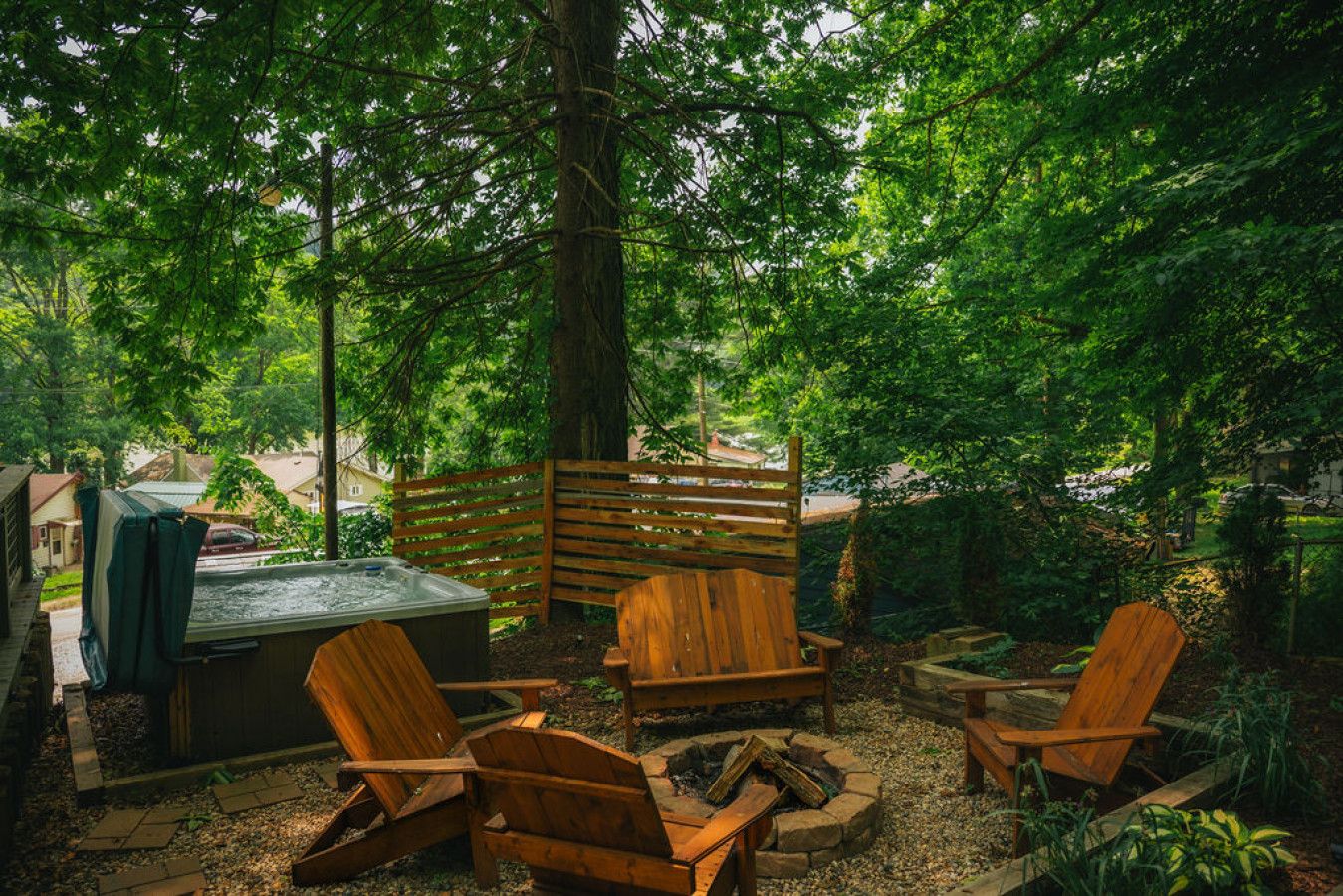 An outdoor seating area with wooden Adirondack chairs, a fire pit, and a hot tub.